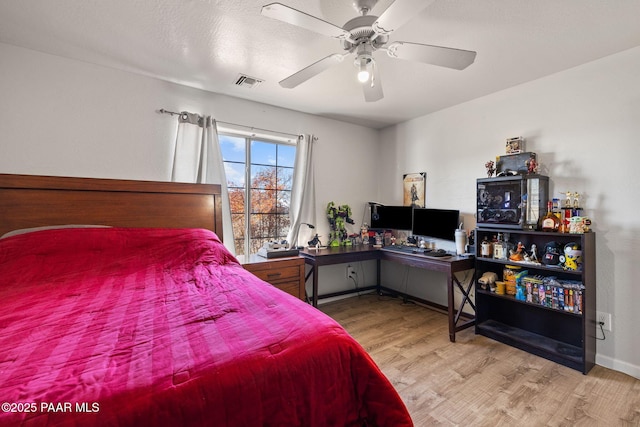 bedroom with ceiling fan, hardwood / wood-style floors, and a textured ceiling