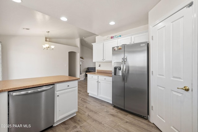 kitchen featuring decorative light fixtures, white cabinetry, appliances with stainless steel finishes, and vaulted ceiling