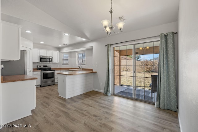 kitchen featuring white cabinets, lofted ceiling, kitchen peninsula, and stainless steel appliances