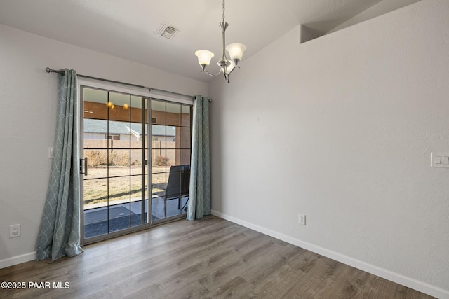 empty room with hardwood / wood-style floors, an inviting chandelier, and lofted ceiling