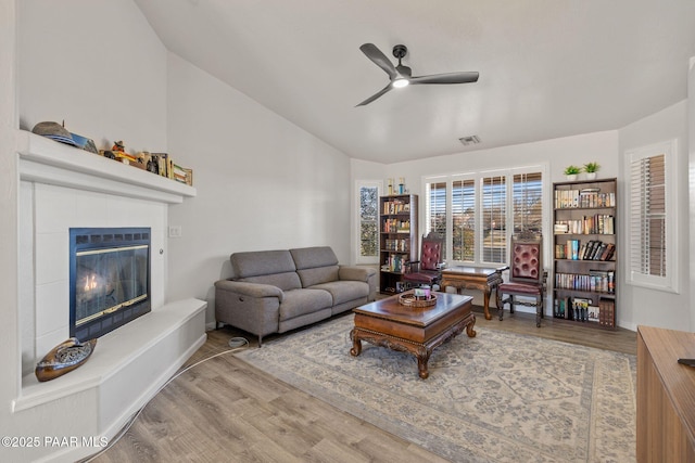 living room featuring a tile fireplace, hardwood / wood-style floors, ceiling fan, and lofted ceiling