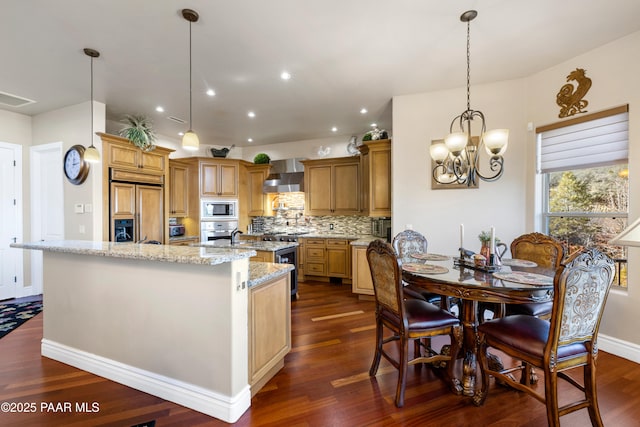 791 N Creekside Dr, Prescott, AZ 86303 - kitchen featuring built in appliances, wall chimney range hood, an island with sink, dark wood-style flooring, and backsplash