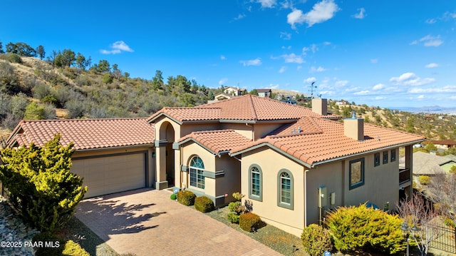 791 N Creekside Dr, Prescott, AZ 86303 - mediterranean / spanish-style house featuring a chimney, an attached garage, a tiled roof, stucco siding, and driveway