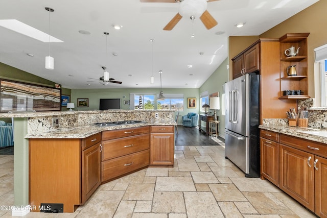 kitchen with a spacious island, hanging light fixtures, vaulted ceiling, light stone counters, and stainless steel appliances