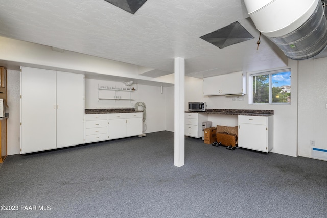 basement featuring dark carpet and a textured ceiling