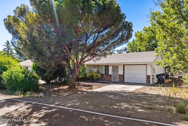 7869 Spouse Dr, Prescott Valley, AZ 86314 - view of front of home featuring concrete driveway, a garage, brick siding, and roof with shingles
