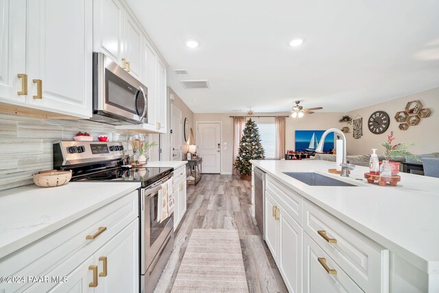 kitchen featuring sink, light hardwood / wood-style flooring, ceiling fan, white cabinetry, and stainless steel appliances