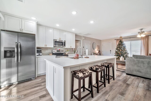 kitchen featuring white cabinets, a center island with sink, and stainless steel appliances