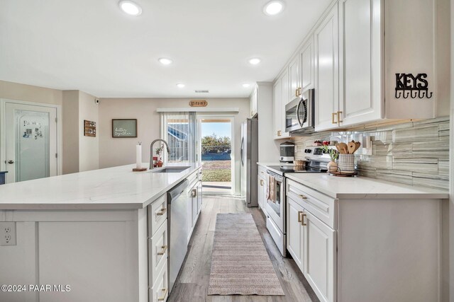 kitchen with white cabinets, sink, light hardwood / wood-style flooring, light stone countertops, and stainless steel appliances