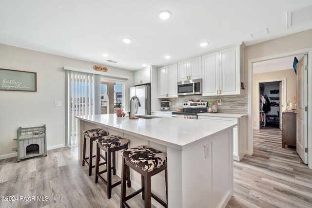 kitchen with appliances with stainless steel finishes, white cabinetry, light hardwood / wood-style flooring, and sink