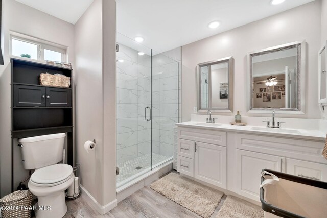 bathroom with vanity, a shower with door, ceiling fan, toilet, and wood-type flooring