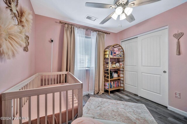 bedroom with a closet, ceiling fan, dark hardwood / wood-style flooring, and a nursery area