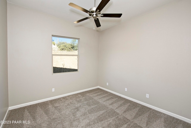 carpeted spare room featuring baseboards and a ceiling fan