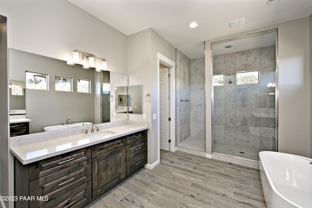 full bathroom with a stall shower, vanity, a soaking tub, wood finish floors, and recessed lighting