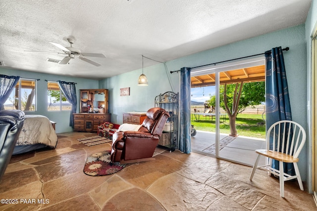 3900 W Runway Rd, Paulden, AZ 86334 - bedroom with access to exterior, a textured ceiling, stone finish floors, and a ceiling fan