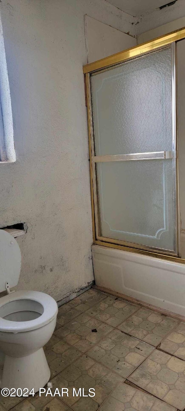 bathroom featuring shower / bath combination with glass door and toilet