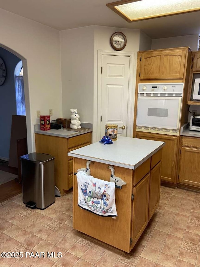 1350 W Justray Ranch Rd, Chino Valley, AZ 86323 - kitchen featuring white oven, light countertops, a center island, and arched walkways