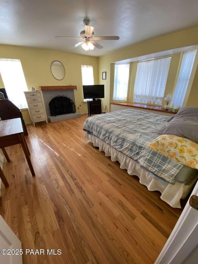 1350 W Justray Ranch Rd, Chino Valley, AZ 86323 - bedroom featuring wood finished floors, a fireplace with raised hearth, and a ceiling fan