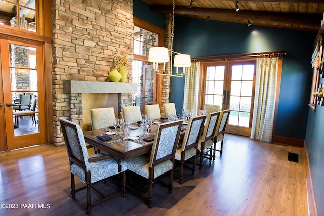 dining area featuring beam ceiling, high vaulted ceiling, a fireplace, wood ceiling, and hardwood / wood-style flooring