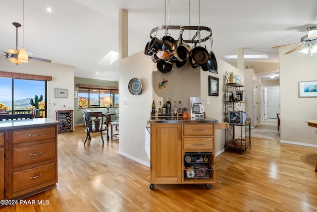 bar featuring light wood-type flooring, lofted ceiling with skylight, and ceiling fan