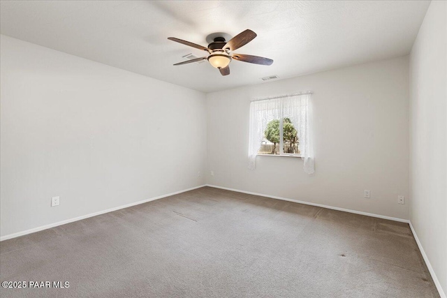 spare room with carpet flooring, a ceiling fan, baseboards, and visible vents