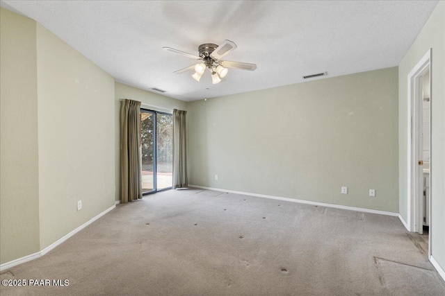carpeted spare room with baseboards, ceiling fan, and visible vents