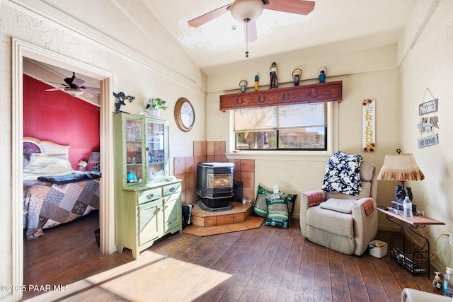 sitting room featuring ceiling fan, wood-type flooring, a wood stove, and vaulted ceiling