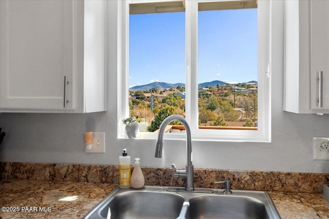 kitchen with sink, white cabinetry, and a mountain view