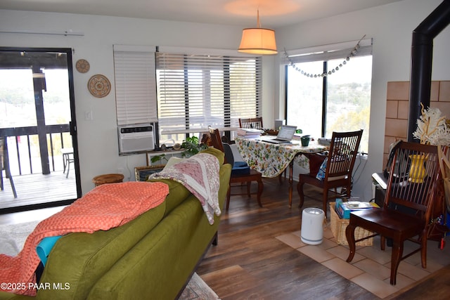 living area with a wood stove, cooling unit, and wood finished floors