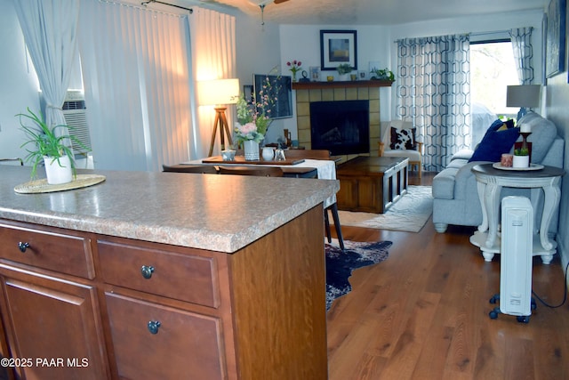 kitchen with open floor plan, cooling unit, a tile fireplace, and wood finished floors