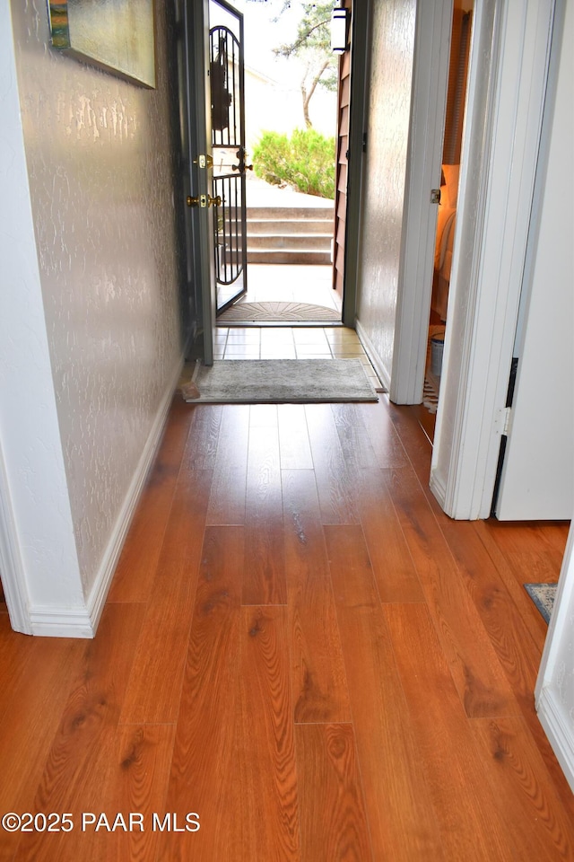 interior space with hardwood / wood-style floors, a textured wall, and baseboards