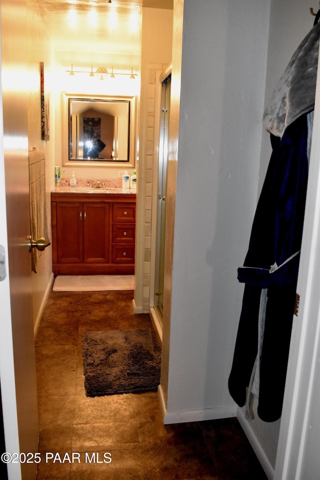 bathroom featuring baseboards, vanity, and a shower stall