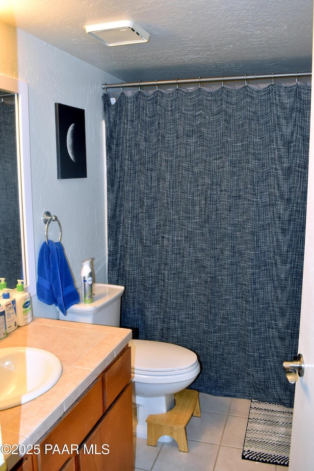 full bathroom featuring vanity, tile patterned flooring, a textured ceiling, toilet, and a textured wall