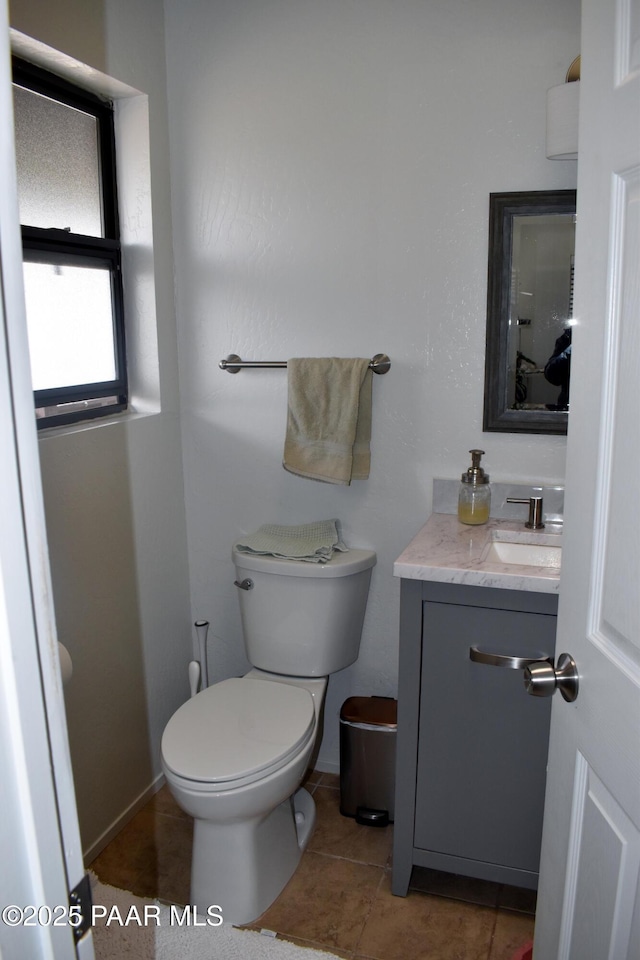 half bathroom featuring vanity, tile patterned floors, and toilet