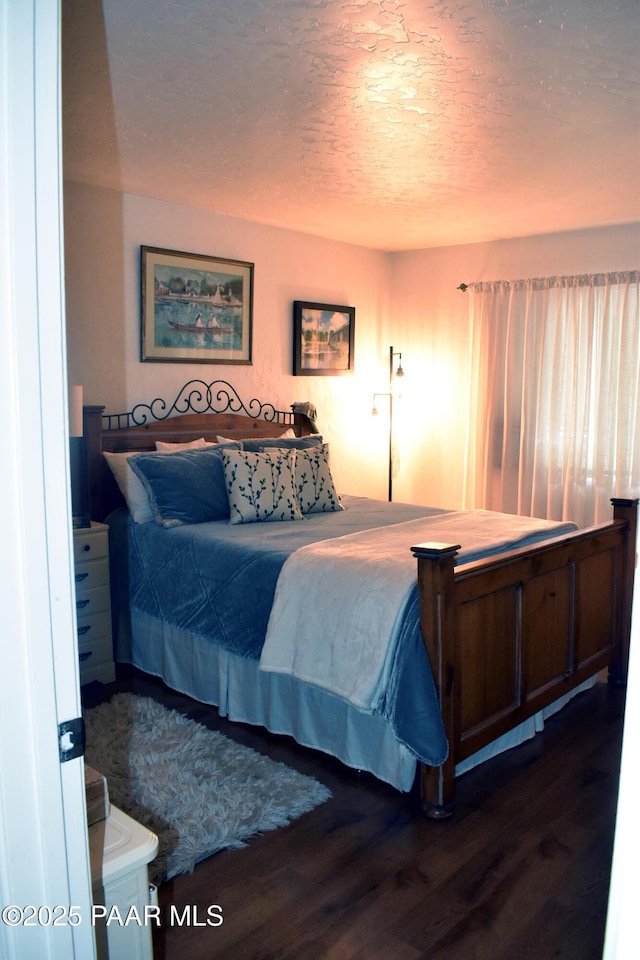 bedroom featuring a textured ceiling and dark wood finished floors