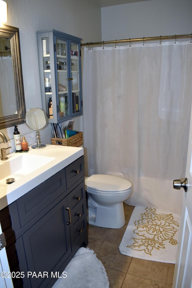 full bathroom with toilet, vanity, and tile patterned flooring