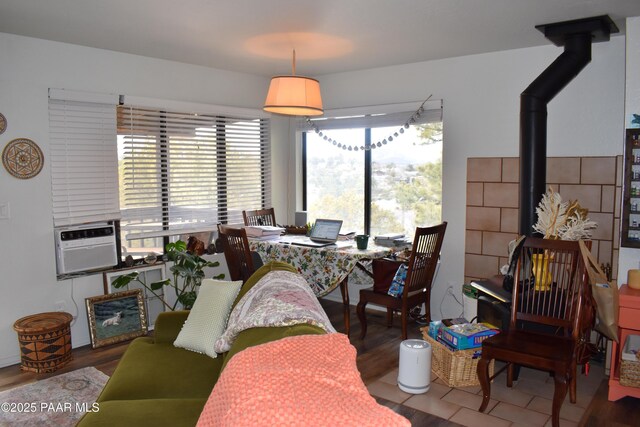 dining area with a wood stove, cooling unit, and wood finished floors