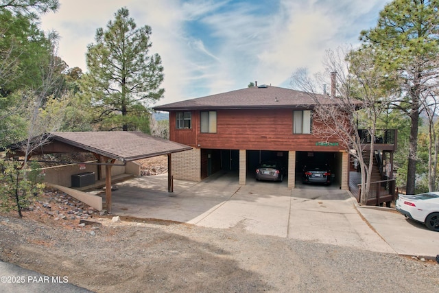 chalet / cabin featuring central AC, stairway, roof with shingles, concrete driveway, and a garage