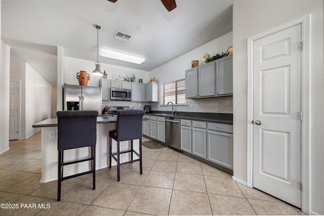 kitchen featuring light tile patterned floors, visible vents, gray cabinetry, appliances with stainless steel finishes, and dark countertops