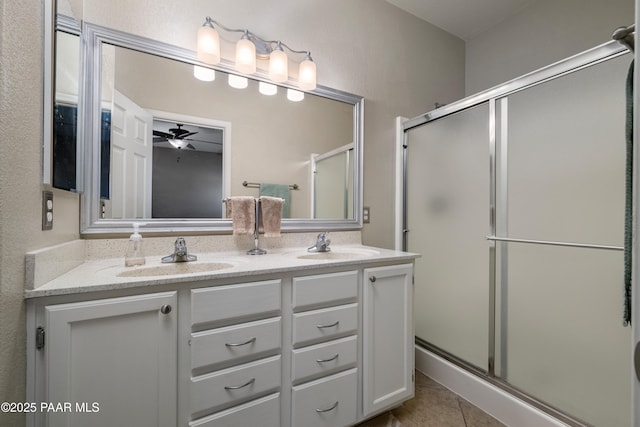 full bathroom featuring double vanity, a shower stall, tile patterned floors, and a sink