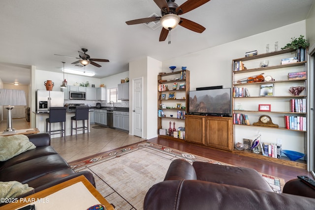 living room with light tile patterned flooring and a ceiling fan