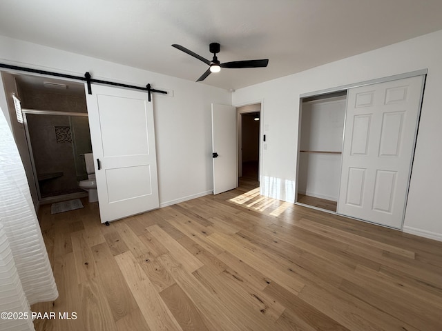 8470 E Sommer Dr, Prescott Valley, AZ 86314 - unfurnished bedroom featuring light wood-style floors, a barn door, a closet, baseboards, and a ceiling fan