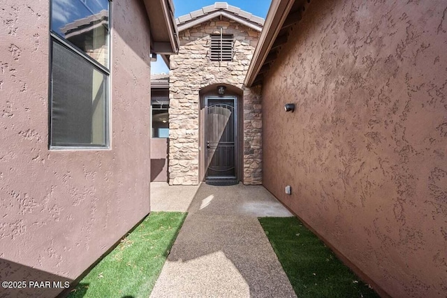 doorway to property with stone siding and stucco siding