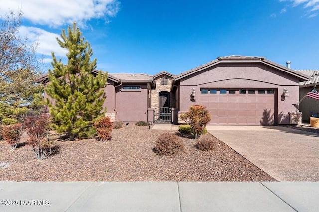 ranch-style home featuring stone siding, driveway, a tiled roof, a gate, and stucco siding