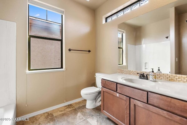 bathroom featuring baseboards, plenty of natural light, vanity, and toilet