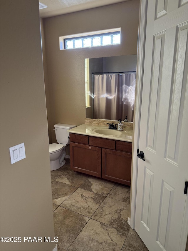 bathroom featuring toilet, a shower with shower curtain, and vanity