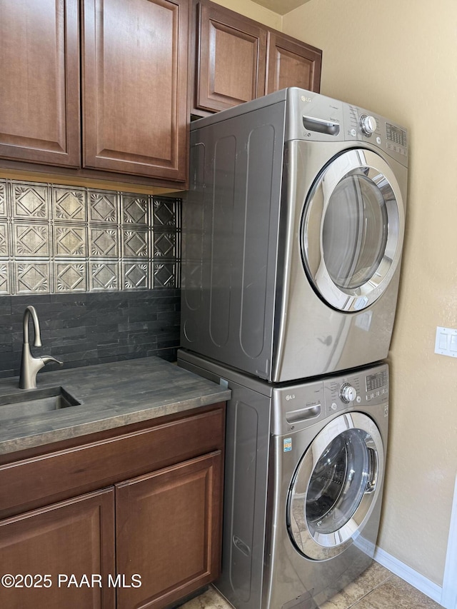 laundry room featuring cabinets, light tile patterned floors, stacked washer / drying machine, and sink