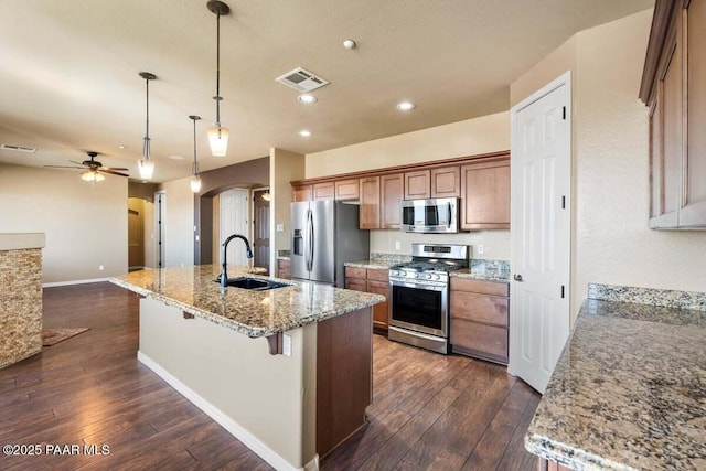 kitchen with arched walkways, dark wood-type flooring, a sink, visible vents, and appliances with stainless steel finishes