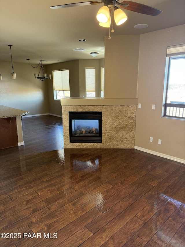 unfurnished living room featuring a fireplace, dark hardwood / wood-style flooring, and ceiling fan with notable chandelier