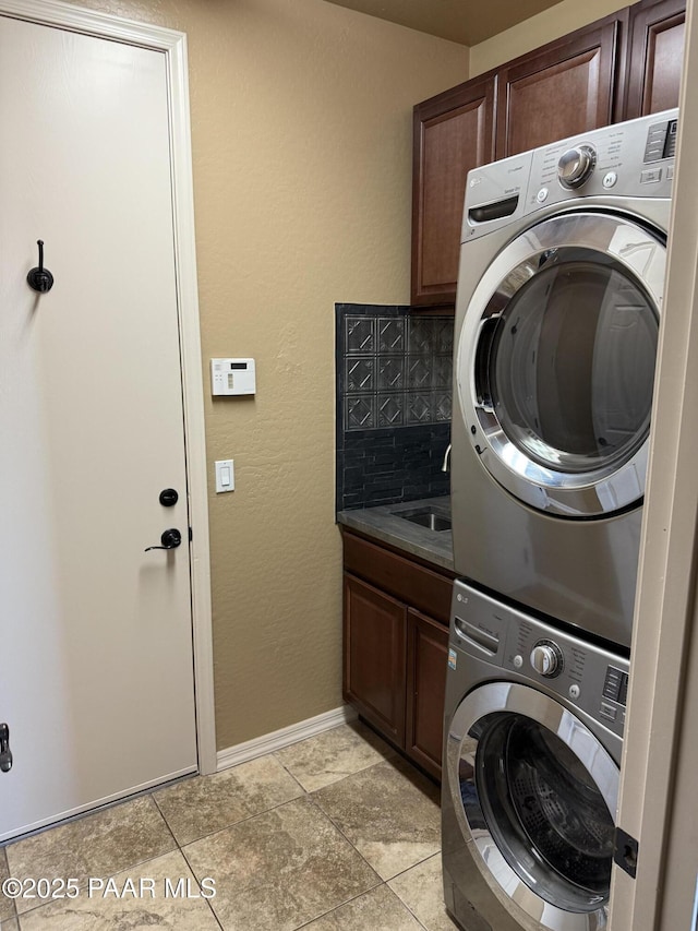 washroom with stacked washer and dryer, cabinets, and sink